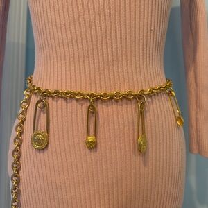 A vintage gold chain belt with a medallion safety pin accent.